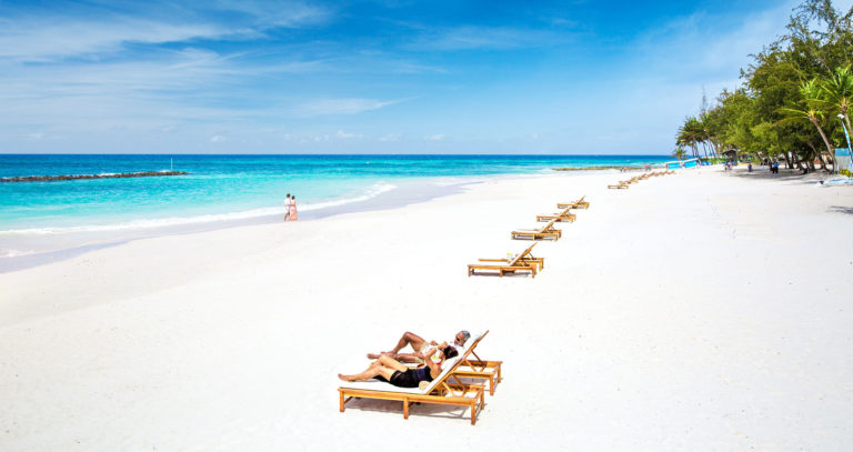 A Clear Sand Beach With People Sleeping